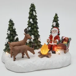 Père Noël et ses rennes au coin du feu lumineux village